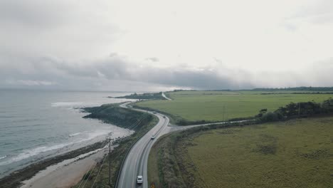 Drone-Siguiendo-Una-Carretera-Donde-Los-Coches-Pasan-Frente-A-La-Costa-De-Paia,-En-La-Isla-De-Maui,-Hawaii