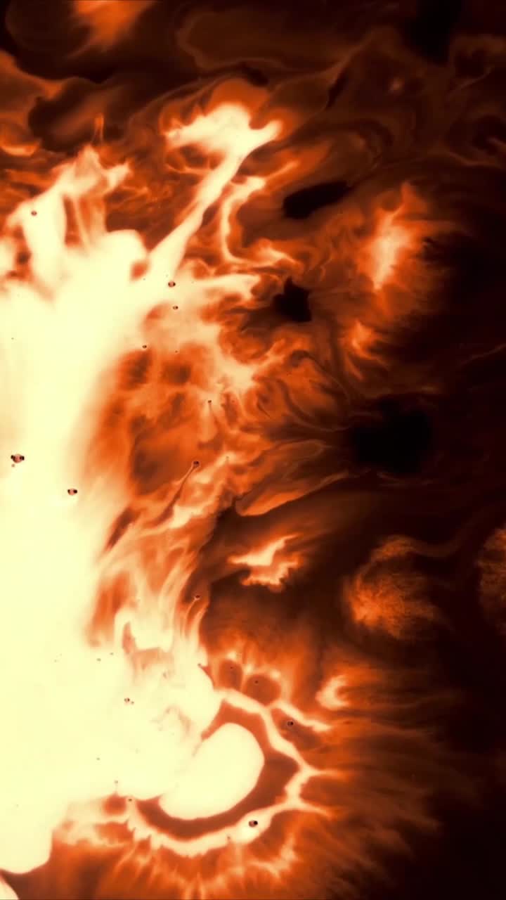 Feurige orange und gelbe Tinte breitet sich auf schwarzem Hintergrund aus