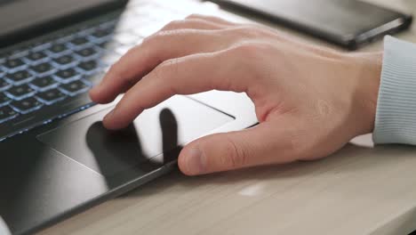 close-up on the hands of the male working with laptop, using finger to customize the cursor and with keyboard for typing touch