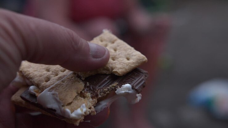 Mangiando un marshmallow e tenendolo in mano.