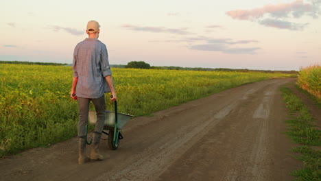 farmer walking in a field with a wheelbarrow