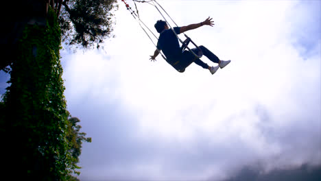 slomo of young man on swing at the end of the world in cloudy ecuador