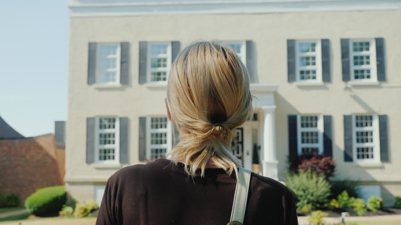 공식적인 옷을 입은 여성이 사무실 건물 o의 건물 후면 입구를 향해 걷고 있습니다.