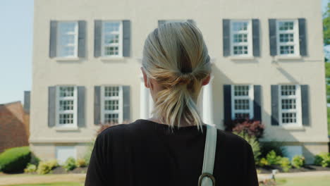 a woman in formal clothes is walking towards the building rear view entrance to an office building o