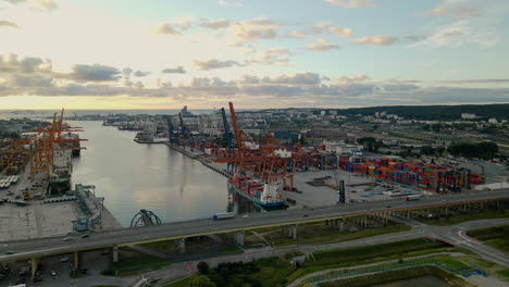 Toma-Aérea-Del-Astillero-De-Carga-Industrial-Con-Grúas-De-Colores-Al-Lado-De-La-Carretera-En-Gdynia,-Polonia