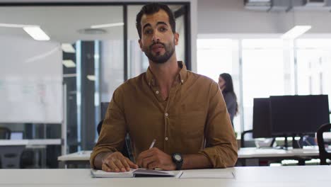 Mixed-race-businessman-sitting-at-desk-having-video-call-gesturing