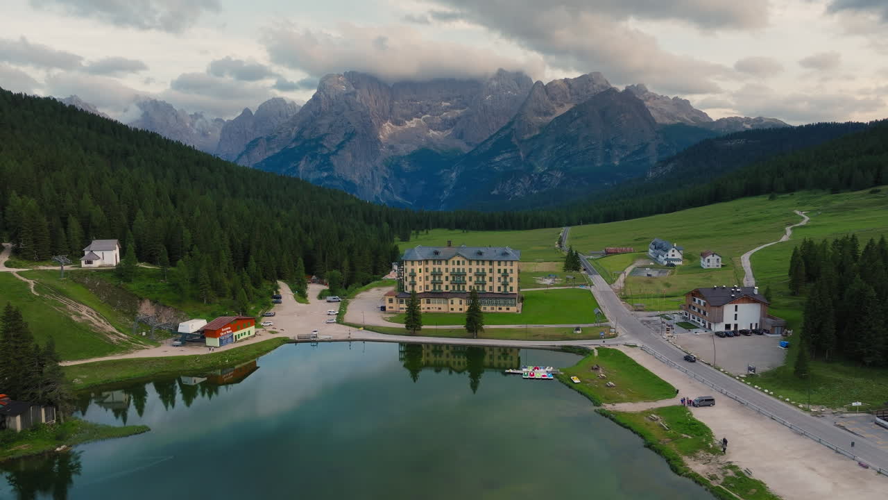 Lago di Misurina natural lake in Dolomites surrounded by alpine mountains and coniferous forests at sunset, Drone shot