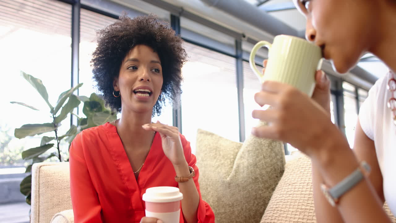 African American and biracial businesswomen enjoying coffee together in office