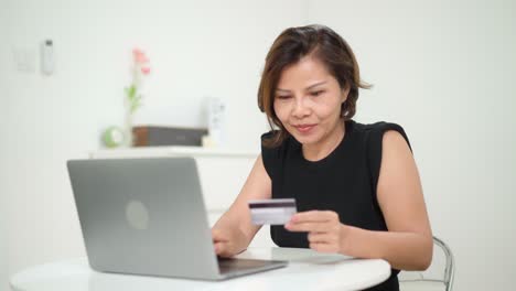 mujer haciendo compras en línea usando tarjeta de crédito en casa