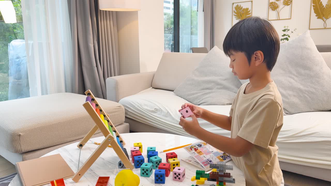 Young Asian boy playing with colorful math dice, learning in a bright living room