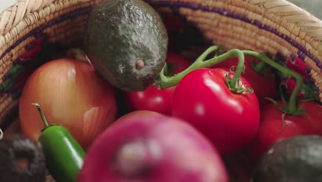 a close-up view of fresh vegetables in a woven basket, featuring tomatoes, avocado, onion, and jalapeño, evoking freshness and organic food concepts