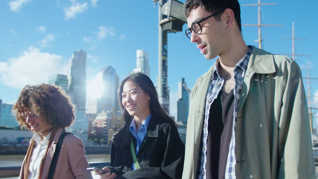 Company of Young Colleagues Walking on Riverbank, Smiling and Talking in the City