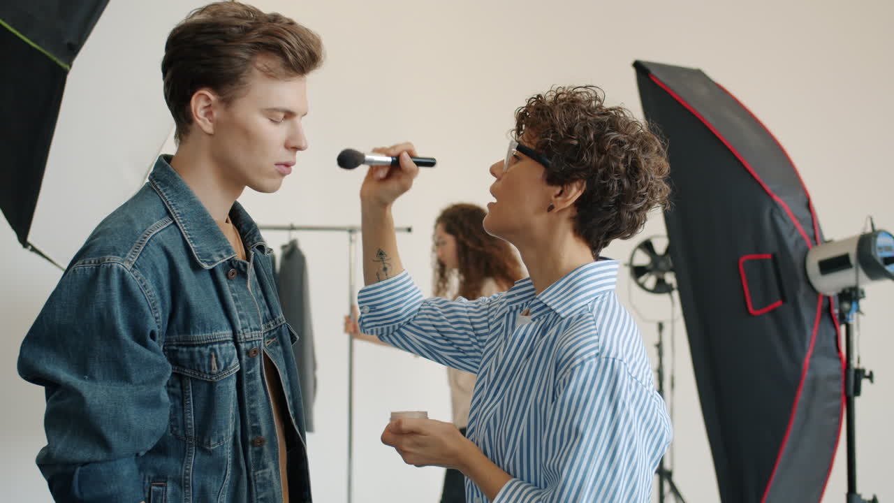 artista de maquillaje aplicando maquillaje a un modelo en un estudio