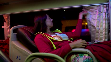 mujer en un autobús de sueño baja el respaldo del asiento, cierra la ventana con una cortina y se pone una máscara