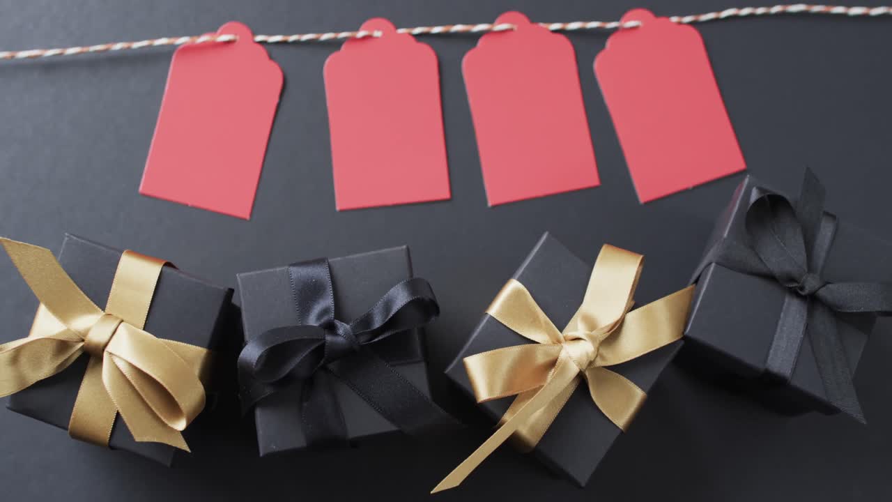 줄에 있는 선물 태그, 리본이 있는 선물 상자 및 검은색 배경에 있는 복사 공간의 비디오