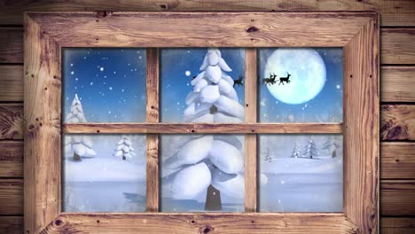 Wooden-window-frame-against-snow-falling-over-multiple-trees-on-winter-landscape