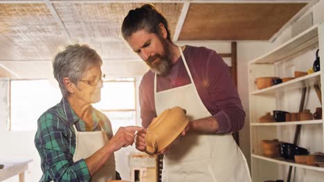 Male-and-female-potter-interacting-while-examining-a-pot