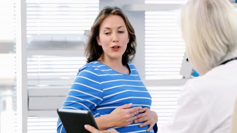 Doctora-Interactuando-Sobre-Una-Tableta-Digital-Con-Una-Mujer-Embarazada