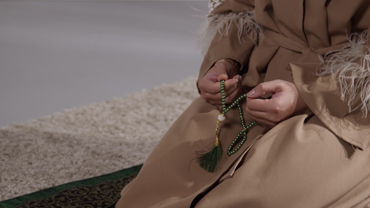 집에서 기도 구슬을 가지고 있는 무슬림 여성이 기도 매트 1에 무을 고 기도하고 있다.
