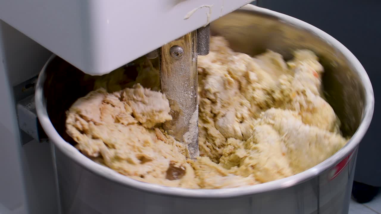 Industrial mixer machine kneading a huge dough batch in close up shots