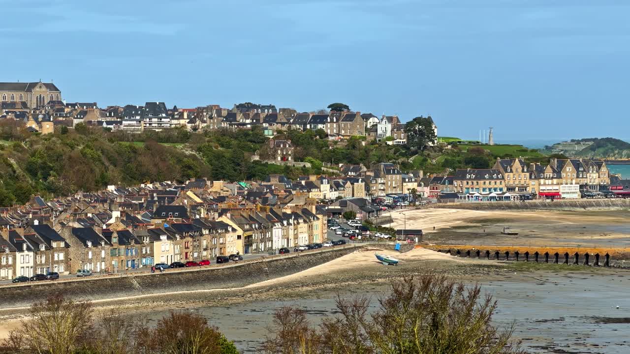 Des rangées de maisons et une église sur une colline surplombent le littoral pittoresque de Cancale, France. Idéal pour les documentaires de voyage ou les reportages culturels.