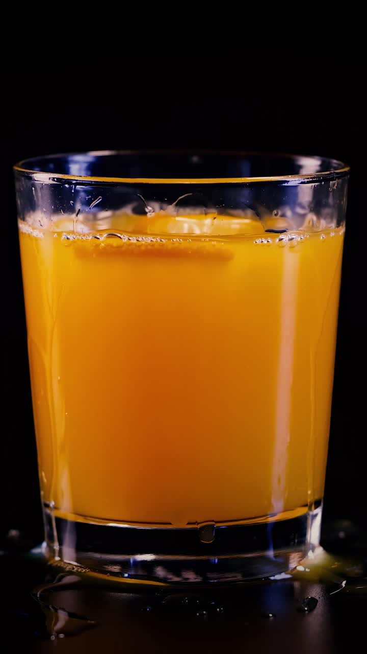 Succo d'arancia che schizza in un bicchiere su sfondo nero
