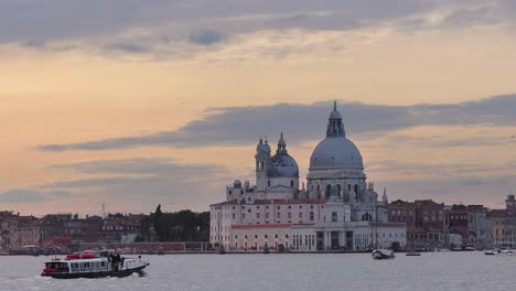 golden sunset of the grand canal of Venice with ships and boats crossing by and punta della Dogana art museum inn the background