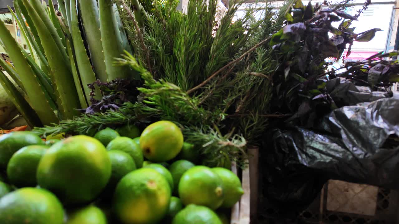 Farmers market stall display fresh produce, green limes, rosemary, and aloe vera,