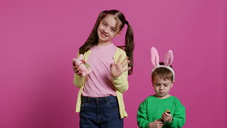 cute brother and sister posing against pink background in studio