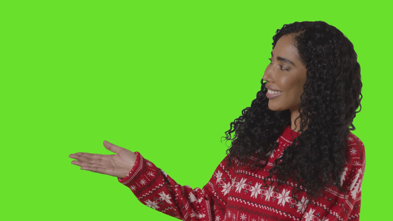 Studio Portrait Of Woman Wearing Christmas Jumper Showing Item Or Object Against Green Screen Smiling At Camera 1