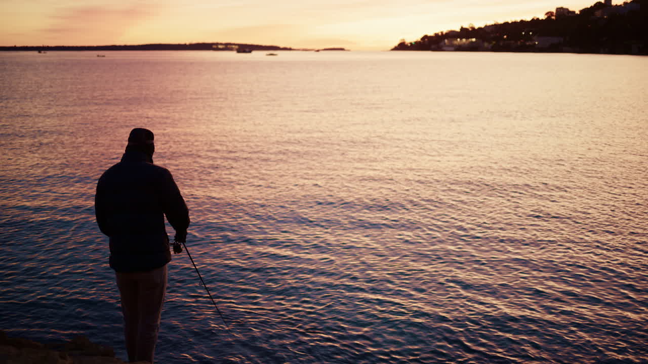 Silhouette of a man fishing in the calm Mediterranean Sea at sunrise in the South of France