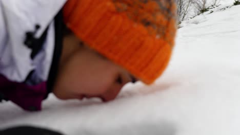 Slow motion of a woman making an imprint of her face in the fresh snow