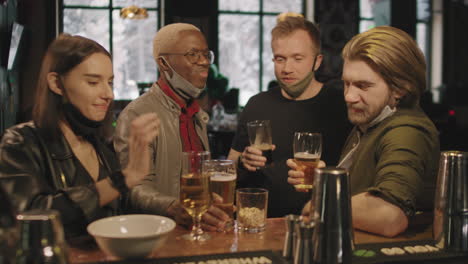 friends making toast with glasses of beer at bar