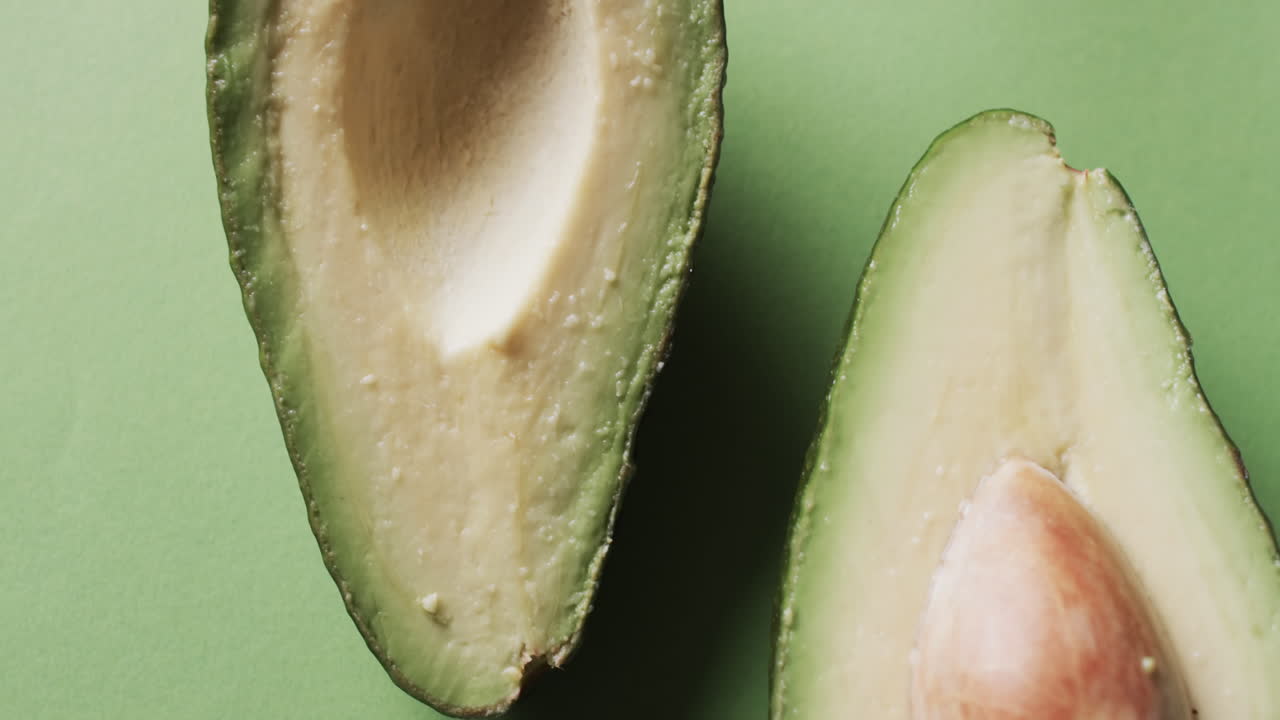 녹색 배경 위 에 복사 공간 을 가진 조각 된 아보카도 의 비디오