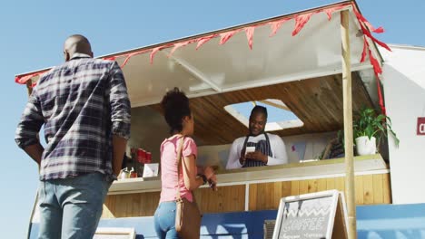 hombre afroamericano que lleva un delantal tomando el pedido de una mujer en el camión de comida