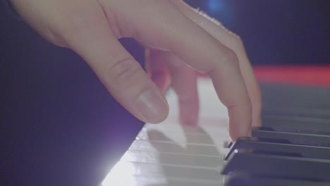 close up of a keyboard players hands playing on an electric stage piano synthesizer keyboards buttons, knobs and faders