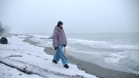 Schöne-Frau-Geht-An-Einem-Kalten-Wintertag-In-Zeitlupe-Am-Verschneiten-Strand-Spazieren