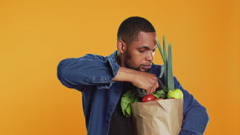 young person scanning fresh organic produce in a paper bag,