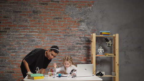 girl drops colored liquid into beaker with teacher in studio