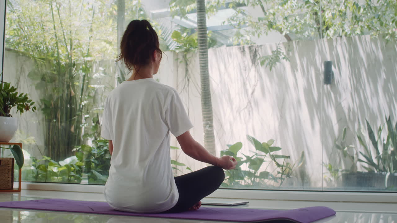 Female Yogi Practicing Lotus Pose in front of Panoramic Windows