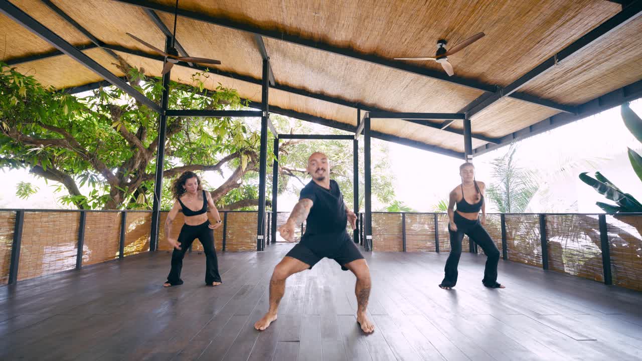 Three People Dancing and Exercising in an Open-Air Tropical Studio