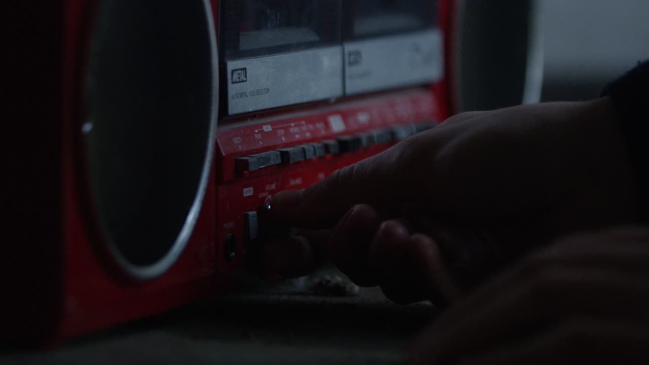 Primo piano di una mano maschile che accende una radio vintage e regola il volume