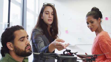 Diverse-group-of-business-colleagues-talking-and-looking-at-drone-in-a-meeting-room