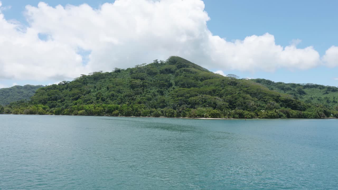 View of on island palm trees and coast from a moving boat on a sunny day in French Polynesia.