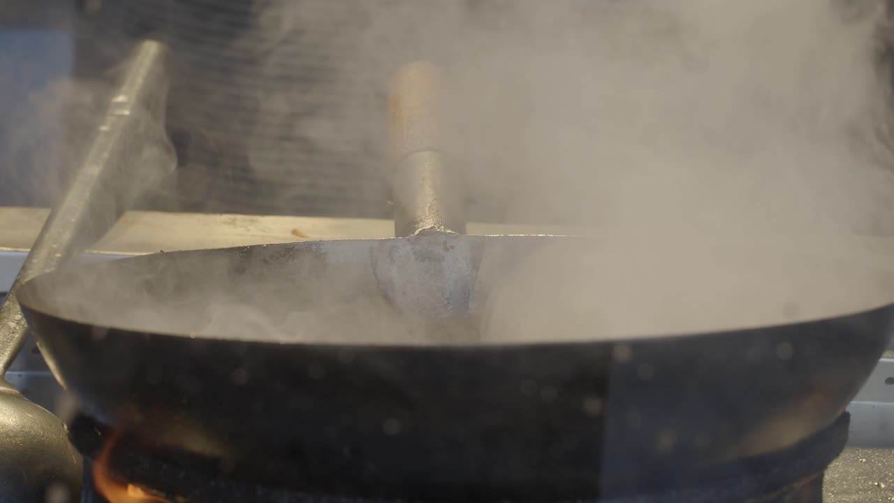Close-up of a steaming wok on a stove