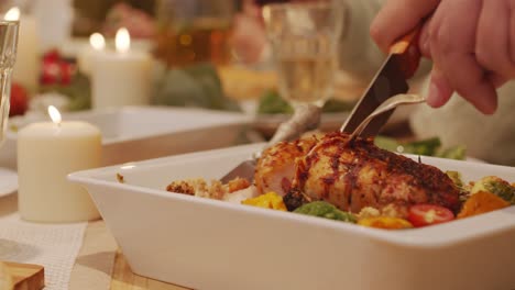 Hands-of-an-unrecognizable-person-with-a-fork-and-knife-cutting-a-delicious-meat-dish-during-a-candlelight-dinner