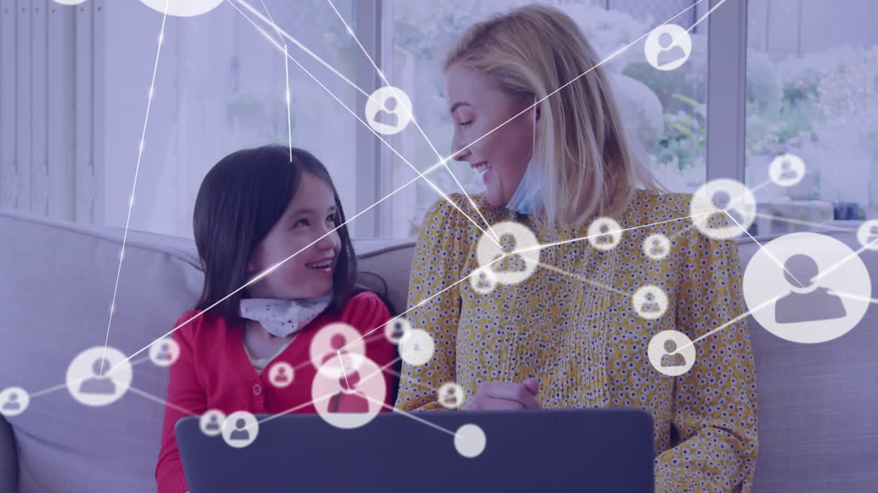 노트북을 사용하여 얼굴 마스크를 쓴 백인 어머니와 딸 위의 미디어 아이콘의 애니메이션