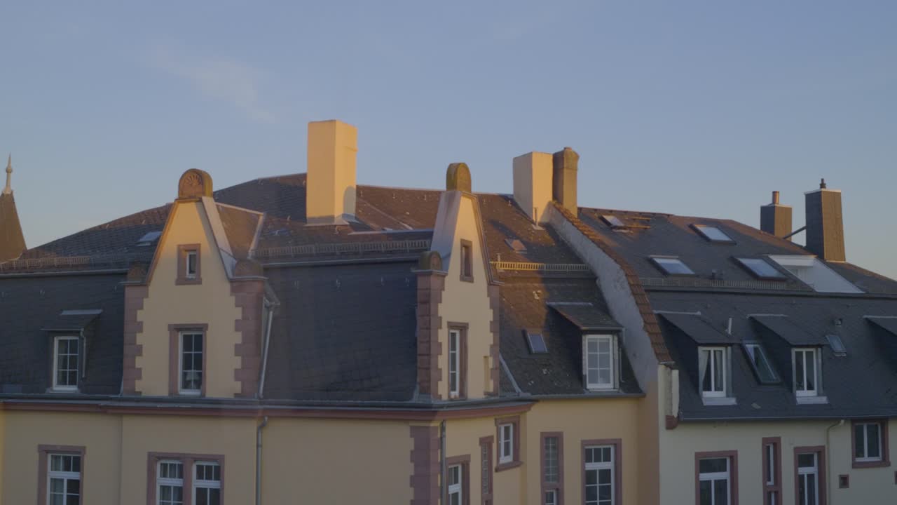 Sunset view of a traditional building rooftop, capturing architecture and chimneys.
