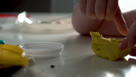 manos de un niño esculpe de masa sobre una mesa blanca