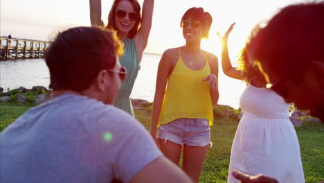 multi ethnic friends playing guitar on sunset beach